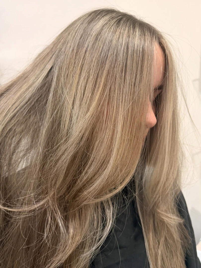 Long blonde hair with soft highlights brushed forward after styling